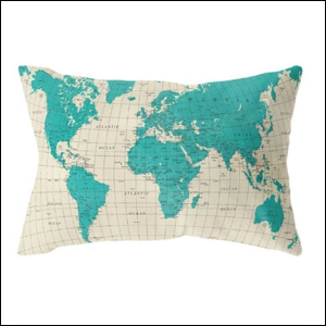 A imagem mostra uma almofada retangular, com uma estampa de mapa mundi. O fundo do mapa é cinza claro, enquanto os países são de cor azul turquesa.
