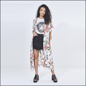 Kimono-Longo-Estampado-YOUCOM Imagem de mulher negra com cabelos cacheados vestindo uma camiseta com estampa P&B e sia jeans preta e, por cima, um kimono longo branco com flores vermelhas.