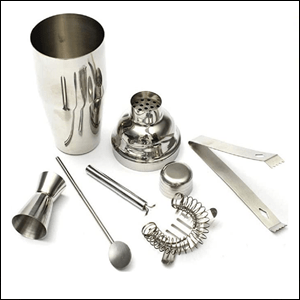 Kit-Bar-Coqueteleira A imagem mostra uma coqueteleira, um pegador de gelo, um coador de bar, um dosador duplo e uma colher de bar, todos em aço inox, num fundo branco.