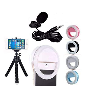 A imagem mostra um tripé preto segurando um celular, um celular com uma luz circular de led presa em sua parte superior, um microfone de lapela enrolado, na cor preta e 4 ring lights. Tudo num fundo branco.