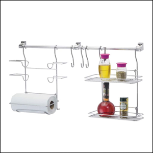 A imagem mostra um conjunto de organização para a cozinha, de aço cromado, com ganchos para pendurar na parede. Ele contém 3 porta rolos, um que está com um papel toalha, três ganchos e duas prateleiras com alguns temperos. O fundo da imagem é branco.