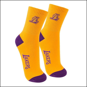 A imagem mostra um par de meias amarelas, com detalhes em roxo de cano médio, com o mascote do time LA Lakers na parte próxima a canela e o nome do time na parte de baixo. O fundo da imagem é branco.