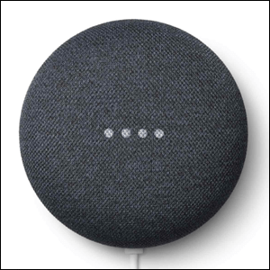 Nest-Mini-Smart-Speaker-2a-geração A imagem mostra o alto-falante Nest Mini, que tem um formato redondo, na cor cinza. É possível ver 4 pontos brancos em cima do alto falante, demonstrando que ele está ligado. O fundo da imagem é branco.