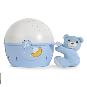 Projetor-Berço-Next-2-Stars-Chicco A imagem mostra um urso de pelúcia azul claro segurando o projetor de luzes, em formato redondo. O projetor é branco em cima e azul embaixo e, no seu centro, há um botão com uma nota musical desenhada em branco e uma lua amarela embaixo do botão. O fundo da imagem é branco.