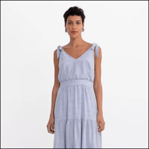 Vestido-Midi-Listrado-da-Marfinno Imagem de mulher morena de cabelos curtos castanhos vestida com vestido longo na cor azul.