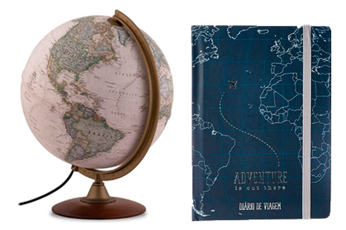 A imagem mostra um globo terrestre na cor branca, com base de madeira e os países em verde, ao lado de um caderno azul escuro com o desenho de uma parte do mapa mundi em branco. O fundo da imagem é branco.