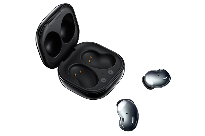 A imagem mostra um par dos fones Galaxy Buds, em formato de feijão, deitados, ao lado de sua caixinha quadrada, arredonda,, na cor preta, com espaço específico para colocar os fones, com o formato deles. O fundo da imagem é branco.
