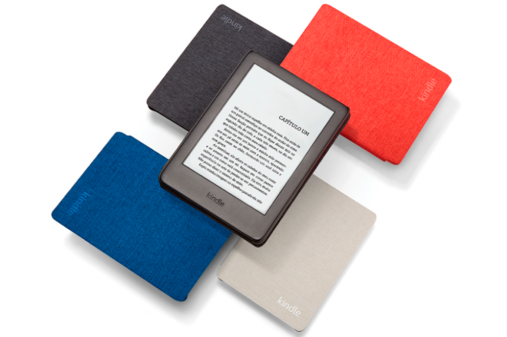 A imagem mostra4 Kindles com diferentes cores de capinha, um preto, um vermelho, um cinza e um azul escuro, dispostos de forma organizada e, em cima deles, há um aparelho Kindle sem capinha, na cor preta, mostrando a tela do capítulo de um livro. O fundo da imagem é branco.