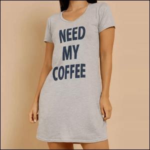 Camisola-Estampada-Manga-Curta-Marisa A imagem mostra uma mulher do pescoço para baixo, usando uma camisola cinza de manga curta, na qual está escrito Need my coffee em azul marinho.