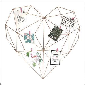 A imagem mostra um aramado na cor rose gold, no formato de um coração, com várias ligações dentro dele, onde estão pendurados diversos cartões com frases e imagens.