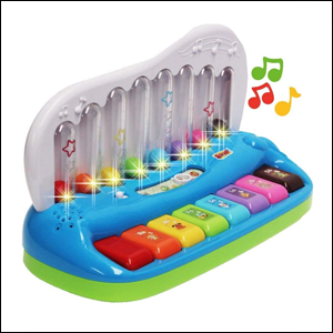 A imagem mostra um teclado infantil colorido, com cada tecla de uma cor e a base na cor azul. Em cima do teclado, há um suporte com recipientes transparentes com uma bola colorida da cor de cada tecla, que se movem quando a tecla correspondente é apertada.