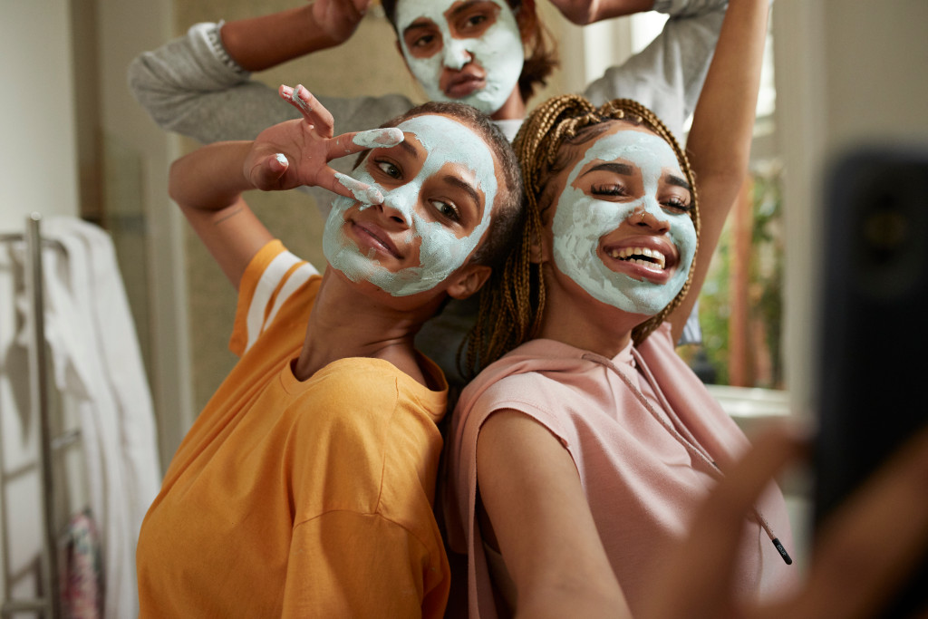 GettyImages-1156020534 A imagem mostra três meninas com máscaras faciais, sorrindo.