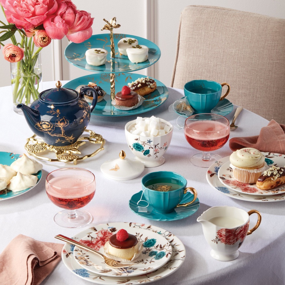 A imagem mostra uma mesa de chá da tarde montada com arranjos florais e coloridos.