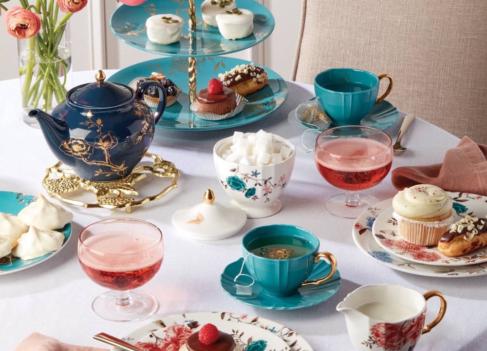 A imagem mostra uma mesa de chá da tarde montada com arranjos florais e coloridos.