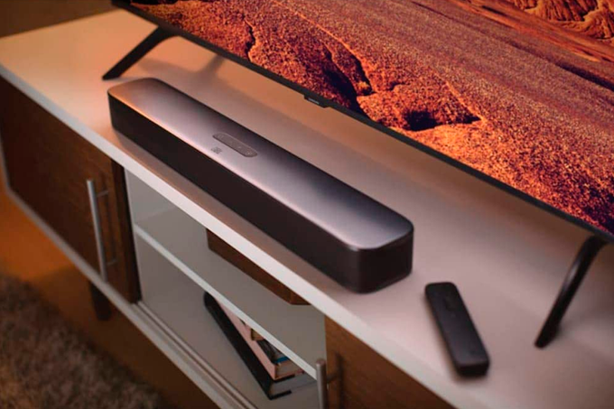 A imagem mostra uma tv em cima de um aparador com um soundbar a sua frente.