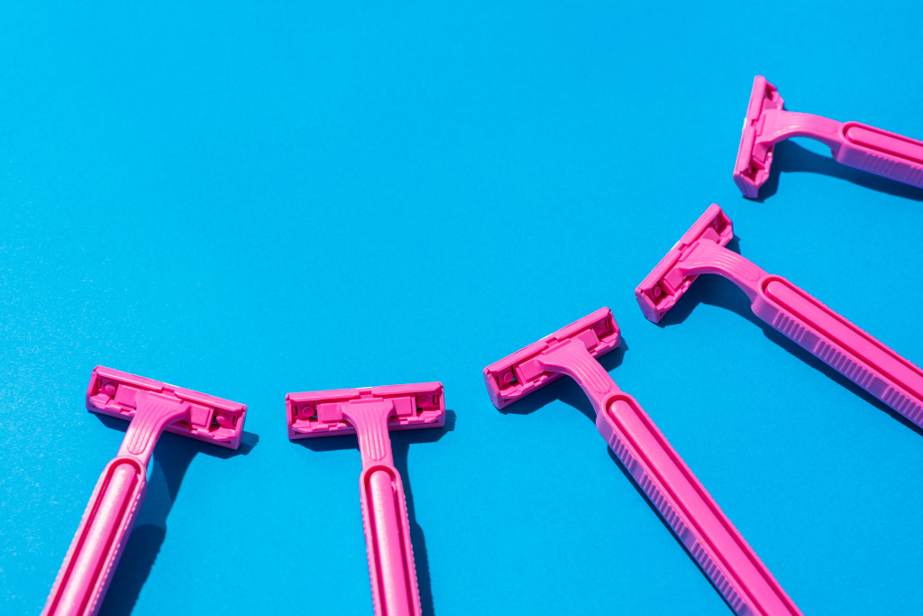 Como-raspar-a-virilha-sem-encravar1 A imagem mostra algumas lâminas de depilação na cor rosa sobre um fundo azul.