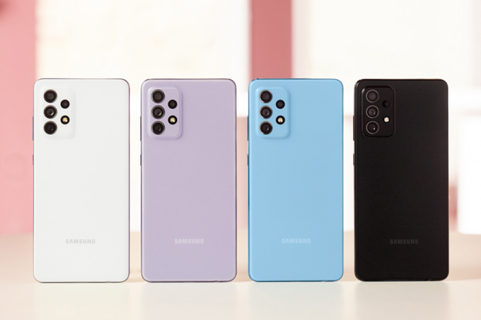 A imagem mostra 4 smartphones Galaxy A72, nas cores branco, lilás, azul e preto, em pé sobre uma mesa branca e um fundo rosa desfocado.
