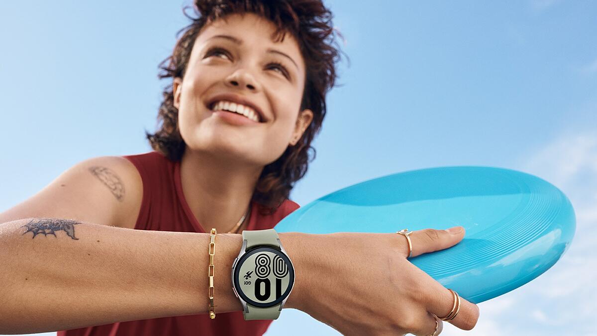 Mulher jovem rindo com um frisbe na mão e um smartwatch no pulso