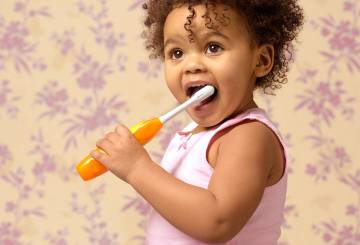 menininha escova os dentes com escova elétrica
