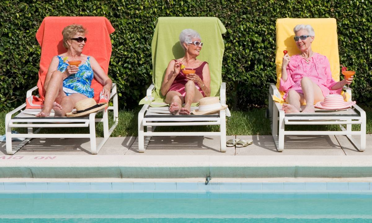 grupo de amigas idosas tomando drinks à beira da piscina