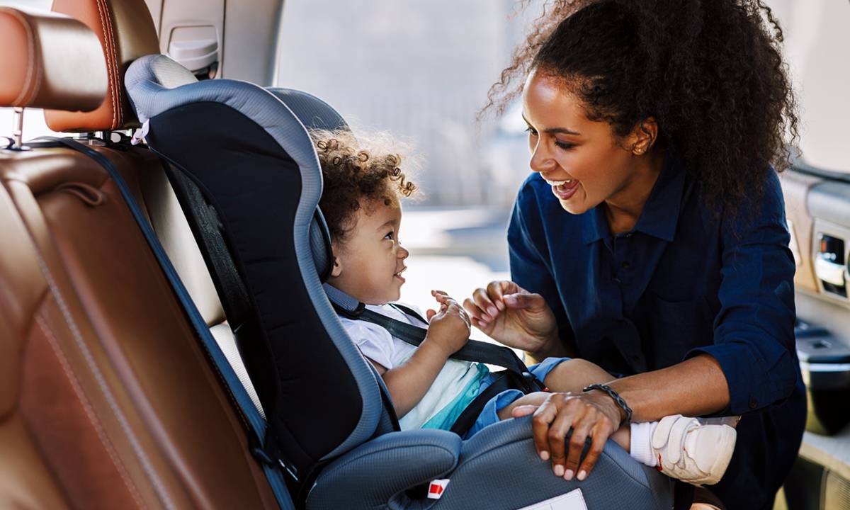 Mãe ajeita bebê na cadeirinha do carro