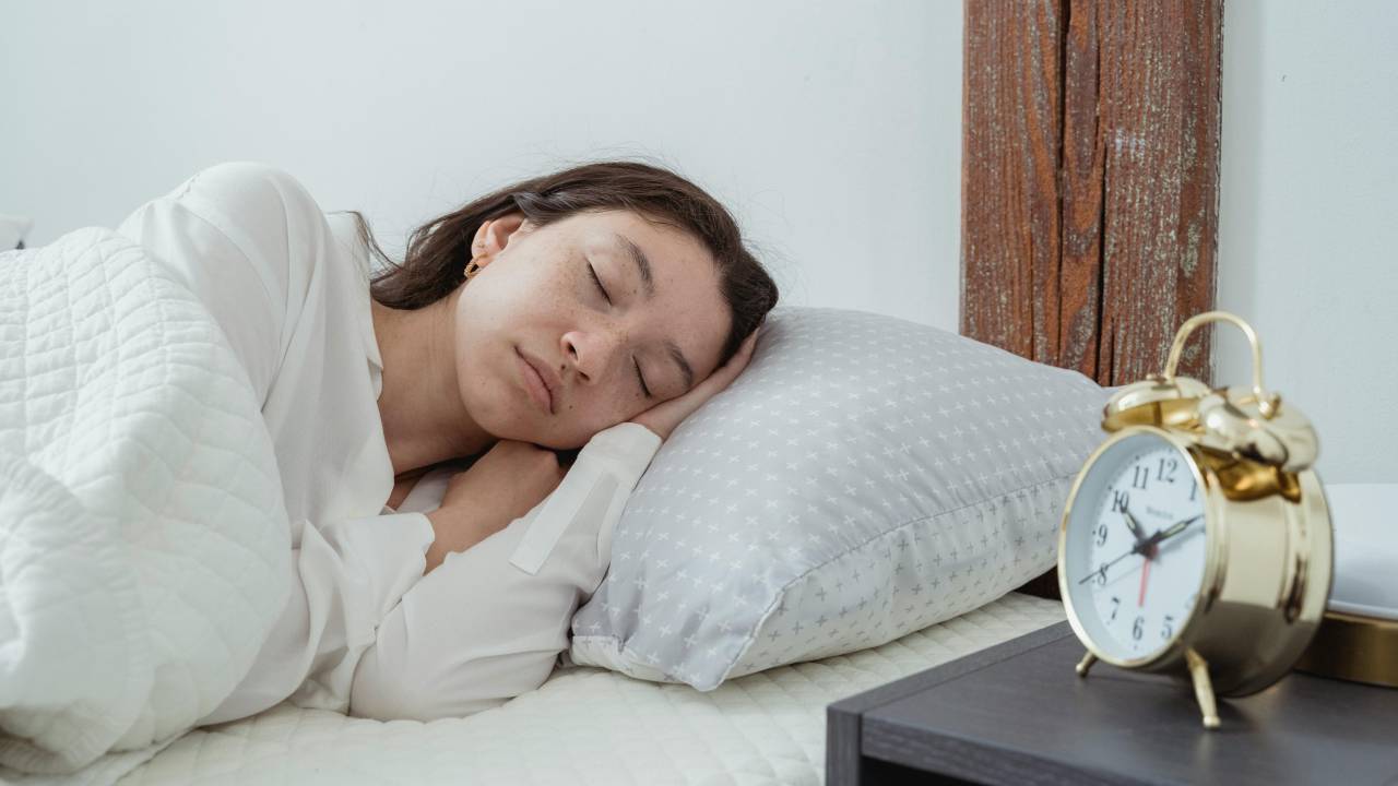 Mulher dormindo com sono na cama e despertador